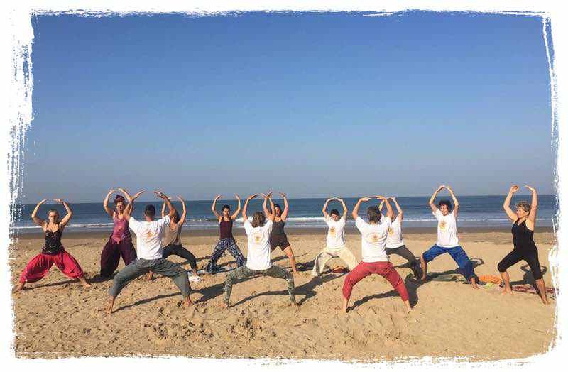 yoga students do hatha yoga in goa at the beach