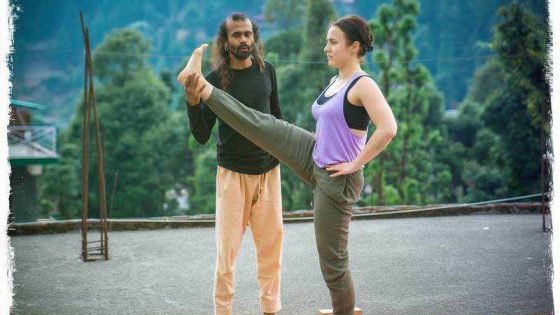 yoga teacher is correcting his student